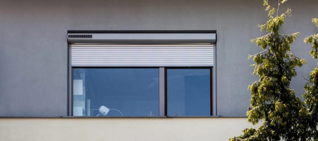 Vue depuis l'extérieur d'une fenêtre de maison avec des volets roulants solaires